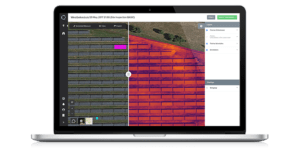 Screen from laptop which shows a ground solarfield from above. Half of the field is normal, the other half is in infrared, measured by drone inspection.